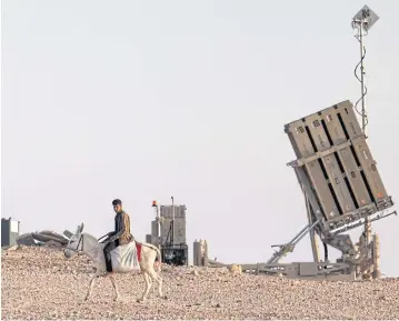  ?? AFP ?? A boy rides a donkey near one of the batteries of Israel’s Iron Dome missile defence system at a village not recognised by Israeli authoritie­s in the southern Negev desert on Sunday.