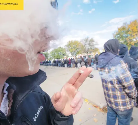  ?? RYAN REMIORZ / THE CANADIAN PRESS ?? A man smokes a joint while waiting outside a government cannabis store in Montreal Wednesday, as the legal sale of marijuana begins in Canada.