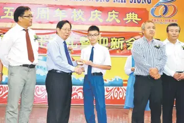  ??  ?? Lau (second left) hands over a study incentive to a new student while Lu (left) and others look on.