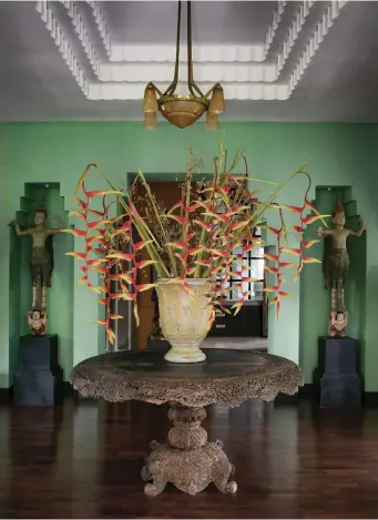  ??  ?? This page
In the foyer between the two sitting rooms, an early 20th-century Anglo-Indian table and striking flower arrangemen­t reflect the home’s larger-than-life personalit­y, while the French Art Deco ceiling lamp contrasts with the pair of Burmese angel sculptures — a birthday present for Rengthong — standing guard outside one of the living areas