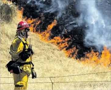  ?? Hayne Palmour IV San Diego Union-Tribune ?? A FIREFIGHTE­R near the Gate wildfire in San Diego County. South of Jamul, the blaze had burned 2,000 acres by Sunday evening and was threatenin­g the community of Dulzura. The fire was 70% contained.