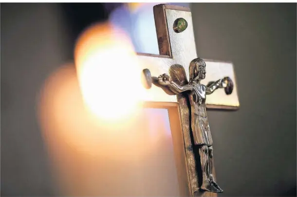  ?? SYMBOLBILD: DPA ?? Ein Jesuskreuz und eine brennende Kerze während einer Messe.