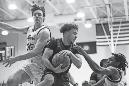  ?? PHOTOS BY MATT STONE/THE COURIER JOURNAL ?? Male guard Max Gainey grabs a rebound under pressure from St. X’s Will Hanke, left, and St. X’s Chief Cameron in the 26th District championsh­ip Thursday night.