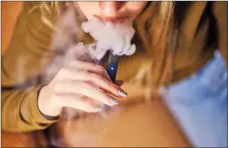  ?? BLOOMBERG PHOTO BY GABBY JONES ?? A person smokes a Juul Labs e-cigarette. U.S. health officials on Friday again urged people to stop vaping until they figure out why some are coming down with serious breathing illnesses. Officials have identified about 450 possible cases, including as many as five deaths, in 33 states. The count includes newly reported deaths in California, Indiana and Minnesota.