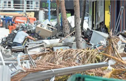  ?? JAY REEVES/AP ?? A man hauls debris away from a pizza restaurant that was destroyed by Hurricane Ian at Fort Myers Beach on Sunday.