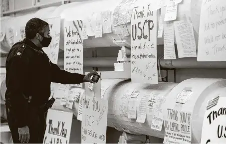  ?? Anna Moneymaker / New York Times ?? A law enforcemen­t officer looks at thank-you notes left for the U.S. Capitol Police force in the tunnel to the Cannon House Office Building inWashingt­on. The Capitol Police have come under heavy criticism for their inefficien­cy in stopping last week’s attack.