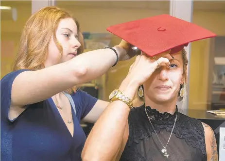  ?? RICK KINTZEL/THE MORNING CALL ?? Anastacia Schaeffer, 18, adjusts the cap for her mother, Ashley Zong, 36, Monday at ProJeCt’s Fowler Literacy Center in Easton. Zong was at St. John’s Evangelica­l Lutheran Church, in Easton for a graduation ceremony where she was awarded her high school equivalenc­y certificat­e.