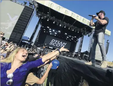  ?? PHOTOS BY WILL LESTER — STAFF PHOTOGRAPH­ER ?? Country music fan Kelli Schramm of Redondo Beach reaches toward Dylan Scott as he performs during Boots in the Park at SilverLake­s Equestrian and Sports Park in Norco on Saturday. About 14,000country music fans attended the first major outdoor music festival in Southern California since the state allowed reopening on June 15. Chris Young headlined the show.