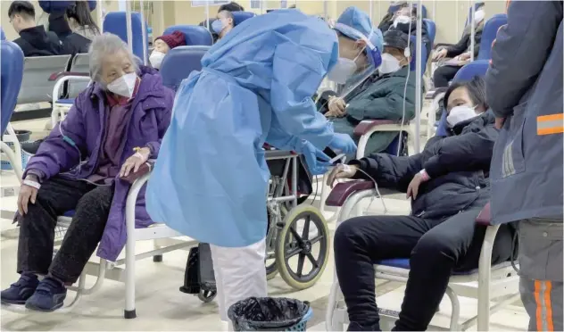  ?? Associated Press ?? ↑
An elderly patient watches a medical worker check on a woman as they receive intravenou­s drips in an emergency ward in Beijing on Thursday.