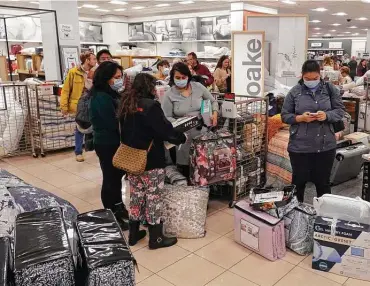  ?? Darron Cummings / Associated Press ?? Customers wait to check out during a Black Friday sale at Macy’s last month in Indianapol­is. Holiday sales rose at the fastest pace in 17 years, even as shoppers dealt with higher prices, product shortages and a new COVID variant.