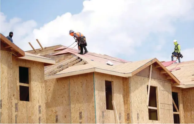  ?? R euters ?? ±
Carpenters work on building new townhomes that are under constructi­on in Florida, US.