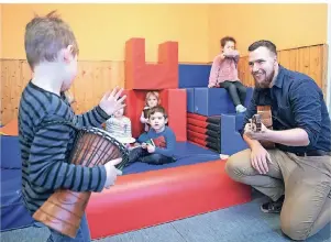  ?? FOTOS (2): BERND THISSEN/DPA ?? Fabian Salin, Erzieher im Dortmunder Kindergart­en Rumpelwich­te, spielt mit Kindern zur musikalisc­hen Früherzieh­ung auf der Gitarre.