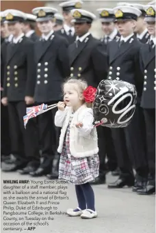  ?? — AFP ?? Young Esme Sutton, daughter of a staff member, plays with a balloon and a national flag as she awaits the arrival of Britain’s Queen Elizabeth II and Prince Philip, Duke of Edinburgh to Pangbourne College, in Berkshire County, on Tuesday on the...