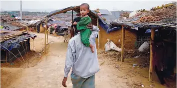  ?? — Reuters ?? A Rohingya refugee man carries a child on his shoulder at the Kutupalang Makeshift Refugee Camp in Cox’s Bazar, Bangladesh, on Thursday.