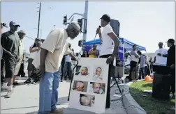  ?? KEVORK DJANSEZIAN/ GETTY IMAGES FILES ?? Pictures of beaten truck driver Reginald Denny are viewed at the intersecti­on of Florence and Normandie avenues at a rally in April.