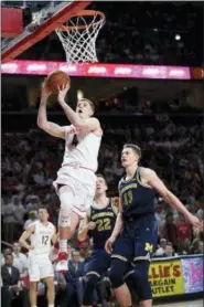  ?? THE ASSOCIATED PRESS ?? Maryland guard Kevin Huerter (4) goes to the basket against Michigan forward Moritz Wagner (13) and guard Duncan Robinson (22) during the second half.