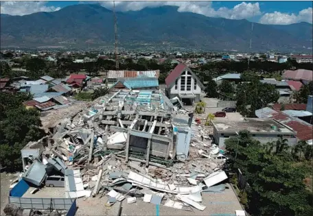  ?? Azwar AFP/Getty Images ?? A 10-STORY hotel in Palu on Sulawesi island lies in ruins. In Palu alone, the death toll was at least 1,193, according to volunteers.