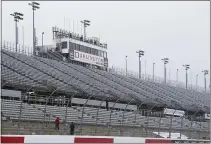  ??  ?? Workers walk along the grandstand­s in the rain at Darlington Raceway after weather forced NASCAR to call off qualifying for the Sprint Cup and Xfinity series auto races. NASCAR says it will resume its season without fans present starting May 17at Darlington Raceway in South Carolina.