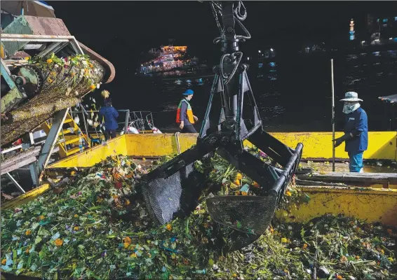  ?? (AP/Sakchai Lalit) ?? Workers collect small floating krathongs Friday from the Chao Phraya River during the Loy Krathong festival in Bangkok.