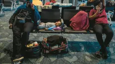  ?? FEDERICO RIOS/THE NEW YORK TIMES ?? Travelers with a baby wait at the airport in Bogotá, Colombia, a busy migrant transit hub.
