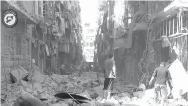  ?? SYRIAN CIVIL DEFENSE WHITE HELMETS VIA AP ?? Syrians survey the damage in Aleppo on Saturday after an escalation in fighting.