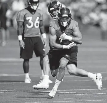  ?? Andy Cross, The Denver Post ?? Broncos running back Phillip Lindsay takes the ball on a hand off from quarterbac­k Case Keenum on the first day of training camp at Dove Valley on Saturday.