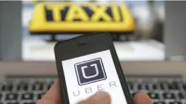  ?? — Reuters ?? An illustrati­on picture shows the logo of car-sharing service app Uber on a smartphone next to the picture of an official German taxi sign, in Berlin, Germany.