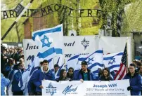  ?? (Agencja Gazeta/Reuters) ?? PARTICIPAN­TS in the March of the Living walk in front of a gate to the Auschwitz concentrat­ion camp earlier this year.