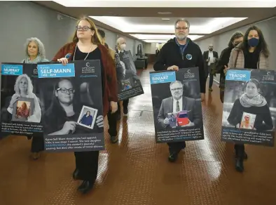  ?? ?? Deb Howland-Murray, from left, of Bridgeport, Kristen Keska, of Southingto­n, Tyrone Biniarz, of Vernon, and Allison Fennelly, of Norwich, carry portraits of themselves with loved ones through the Legislativ­e Office Building, where they will be on display through Jan. 31.