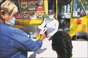  ?? Brian A. Pounds / Hearst Connecticu­t Media ?? Andrea Figueroa, of West Haven, waits on customers at the Tacos Los Michoacano­s food truck at Long Wharf in New Haven late last month. The trucks were forced to close when the coronaviru­s pandemic hit to address health department concerns including the use of masks and social distancing.