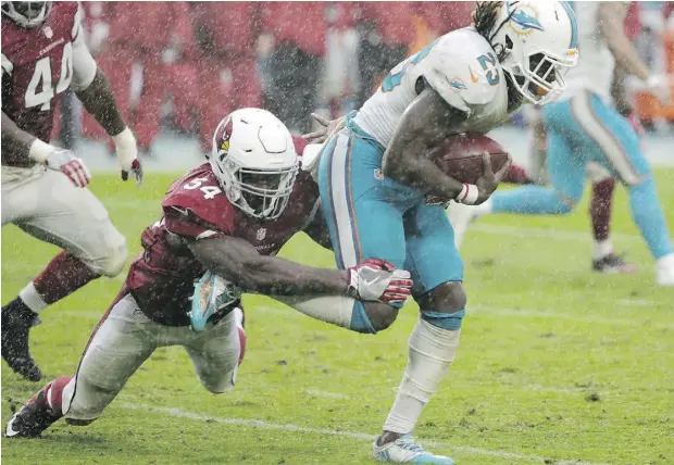  ?? WILFREDO LEE / THE ASSOCIATED PRESS ?? Arizona Cardinals linebacker Sio Moore wraps up Miami Dolphins running back Jay Ajayi during a rain-soaked game Sunday in Miami.