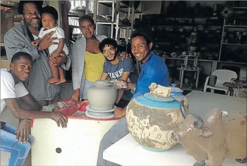  ?? Picture: DAVID MACGREGOR ?? POTTERS’ PRIDE: Swazi-born master ceramicist Meshack Masuku holds his nine-month old son as his workshop apprentice­s, from left, Asiphe Gaxela, 20, Buseka Gaxela, 17, Freddie Luffun, 21, and Sityhilelo Ngozi, 25, look on