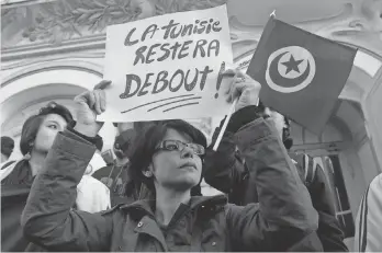  ?? SOFIENE HAMDAOUI, AFP/ GETTY IMAGES ?? A woman holds a placard reading in French, “Tunisia will remain standing” as she takes part in a protest March 18, 2015, after an attack on the National Bardo Museum in Tunis.