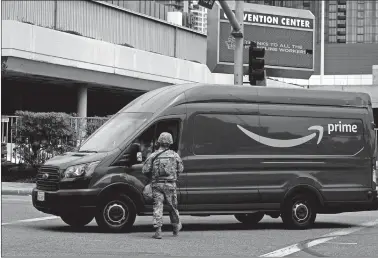  ?? BING GUAN/BLOOMBERG ?? A National Guardsmen speaks with an Amazon.com Prime delivery driver at the Los Angeles Convention Center in downtown Los Angeles in June.