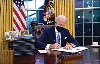  ?? EVAN VUCCI / AP ?? President Joe Biden signs his first executive order in the Oval Office on Wednesday in Washington.