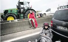  ?? CHRISTOPHE ENA AP ?? Farmers relax at a blockade on a highway on Tuesday in Jossigny, east of Paris. France’s new prime minister announced more concession­s in hopes of defusing farmers’ anger.