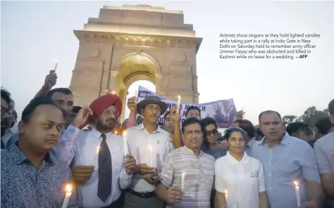  ?? — AFP ?? Activists shout slogans as they hold lighted candles while taking part in a rally at India Gate in New Delhi on Saturday held to remember army officer Ummer Faiyaz who was abducted and killed in Kashmir while on leave for a wedding.