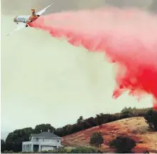  ??  ?? A plane drops retardant over a Lakeport property threatened by a wildfire on Monday.