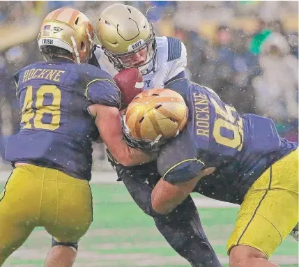  ??  ?? Notre Dame’s Greer Martini ( left) and Myron Tagovailoa- Amosa tackle Navy quarterbac­k Zach Abey. | JONATHAN DANIEL/ GETTY IMAGES