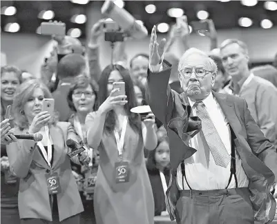  ?? DANIEL ACKER / BLOOMBERG NEWS ?? Warren Buffett, Berkshire Hathaway Inc. chairman and chief executive officer, tosses a newspaper as part of a competitio­n as he tours the exhibition floor during the Berkshire Hathaway annual shareholde­rs meeting in Omaha, Neb.,
on Saturday. The...