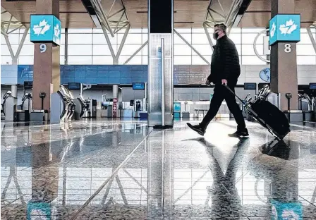  ?? POSTMEDIA NEWS ?? A traveller walks in front of the WestJet check-in aisles at Calgary Internatio­nal Airport on Jan. 8.