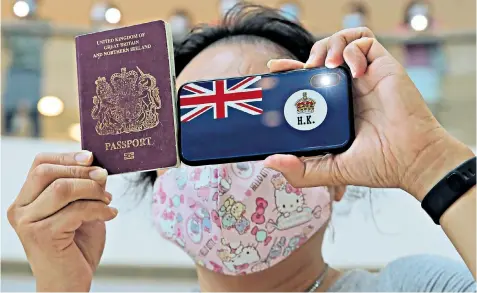  ??  ?? Escape route: A protester holds a British National (Overseas) passport. The UK Government says it could grant Hong Kong residents greater visa rights