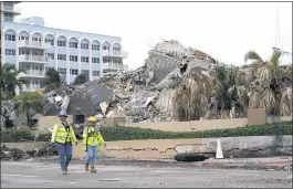  ?? LYNNE SLADKY — THE ASSOCIATED PRESS ?? Workers walk past the collapsed and demolished Champlain Towers South condominiu­m building on Tuesday in Surfside, Fla. Tropical Storm Elsa complicate­d search efforts.