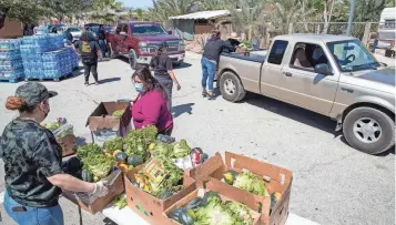  ?? TAYA GRAY/THE DESERT SUN ?? Volunteers distribute food, water and personal protection equipment to farmworker­s and their families in Thermal, Calif., on March 27, 2021.