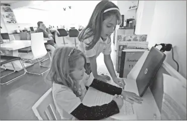  ?? AP- Wilfredo Lee ?? Emily Chao (standing) watches as her sister Anabelle works on a writing exercise after they finished remote learning for the day, as their mom Erica (back left) sits at their home in North Miami Beach, Fla. Rather than wait to see how the Miami-Dade school system would handle instructio­n this fall, Erica Chao enrolled her two daughters in a private school that seemed better positioned to provide remote learning than their public elementary school was when the coronaviru­s first reached Florida.