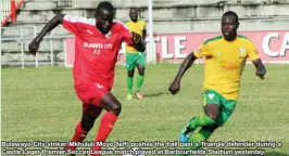  ??  ?? Bulawayo City striker Mkhululi Moyo (left) pushes the ball past a Triangle defender during a Castle Lager Premier Soccer League match played at Barbourfif­ields Stadium yesterday