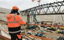  ?? LEWIS JOLY/AP ?? A worker looks at constructi­on on the arena in Porte de la Chapelle, a neighborho­od in Paris that will host badminton and rhythmic gymnastics during the 2024 Olympics.