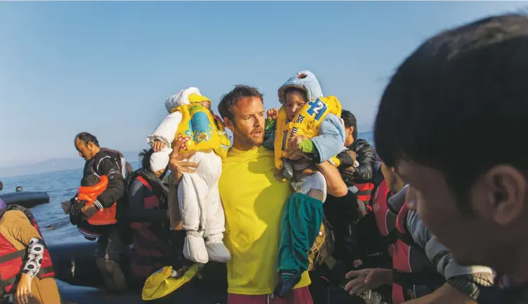  ??  ?? A Spanish volunteer lifeguard helps refugees arrive on the Greek island of Lesbos, photo Ron Haviv