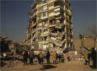  ?? EMRAH GUREL — THE ASSOCIATED PRESS ?? People stand by a collapsed building in Kahramanma­ras, southern Turkey, on Sunday.