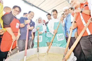  ??  ?? Shafie (third from right) and Malinaziah (third from left) stirring the bubur lambuk during the RTM Ramadan Roadshow at the Ministry of Communicat­ion and Multimedia Integrated Complex in Kepayan yesterday.